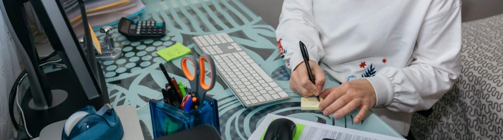 A top-down view of a woman in casual clothes, working at a home-office desk.